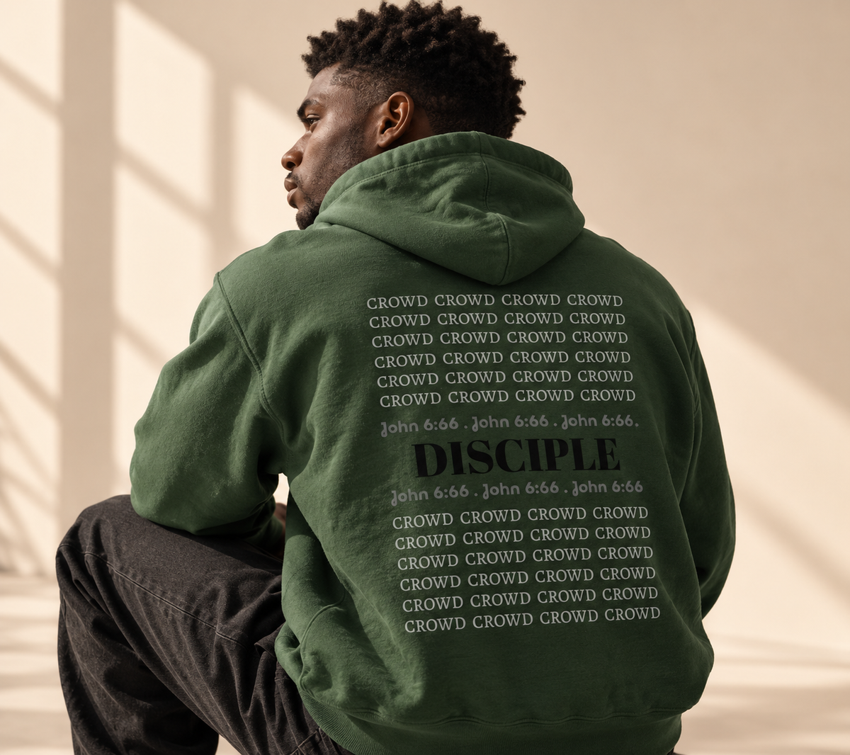Man wearing a forest green Theologie Clothing Crowd to Disciple hoodie, showing the back design.